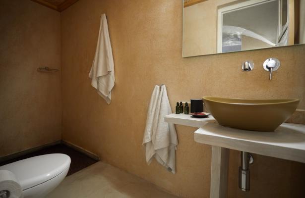 A bathroom in a cellar accommodation in oia santorini featuring a sink toilet and towel rack hu 7b7b1975980f0906.jpg