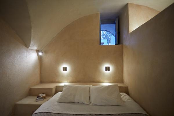 A cozy bed in a cellar accommodation in oia santorini illuminated by two warm lights hu 93d1d3288783e3e8.jpg