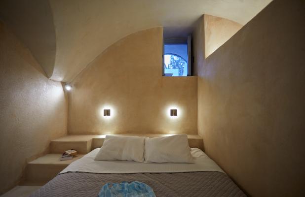 A cozy bed with a white sheet and pillow in a charming cellar accommodation in oia santorini hu4975177862334253823.jpg