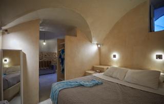 A cozy bedroom in a cellar in oia santorini featuring a bed and a mirror blending charm and comfort hu5934497781952445696.jpg