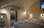 A cozy bedroom in a cellar in oia santorini featuring a bed and a mirror blending charm and comfort hu 2afcfffe93a5935a.jpg