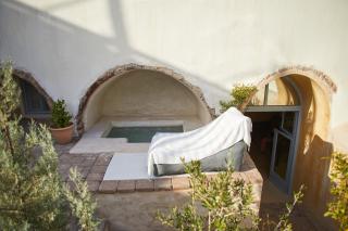 A white towel rests on a chair beside a hot tub in a cellar accommodation in oia santorini hu6497219316318616362.jpg