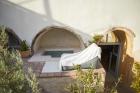 A white towel rests on a chair beside a hot tub in a cellar accommodation in oia santorini hu 647f8c54585854d8.jpg