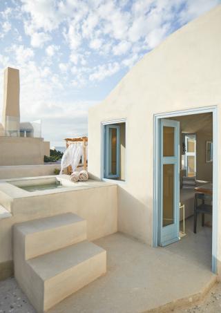 A white house featuring a blue door and a white roof set against a clear sky hu cb542b4efc14fa6b.jpg