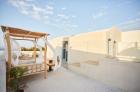 Rooftop terrace with a canopy bed two lounge chairs a small table and white walls under a clear sky hu 7452a9e14b2eb169.jpg