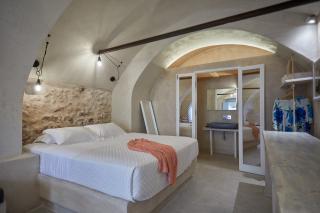 A cozy bedroom featuring a bed and mirror part of a cellar accommodation in oia santorini with a private hot tub and veranda hu5774766887546149099.jpg