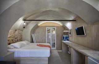 A cozy bedroom in oia santorini featuring a bed tv private hot tub and a veranda with a courtyard view hu e30bd45ef64d3825.jpg