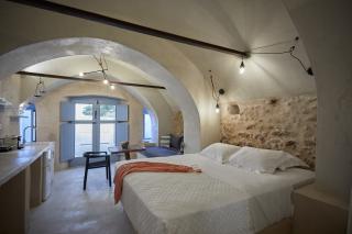A cozy bedroom in oia santorini featuring a stone archway bed private hot tub and a charming veranda 2 hu 2cd90530c919f615.jpg