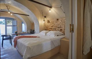 A cozy bedroom in oia santorini featuring a stone archway bed private hot tub and a charming veranda hu16579400026863594793.jpg