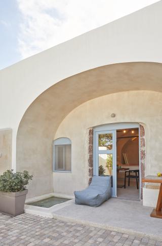 A cozy patio in oia santorini featuring a blue chair and table with a private hot tub and courtyard hu7161279016352497828.jpg