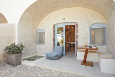 A cozy patio in oia santorini featuring a table and chairs with a private hot tub and courtyard for relaxation.jpg