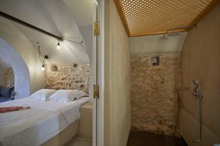 A cozy room in oia santorini featuring a bed shower private hot tub and a veranda with a courtyard hu6546696760724558536.jpg