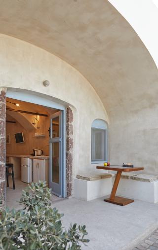 A table and bench in a cozy cellar accommodation in oia santorini featuring a private hot tub and veranda hu 9736426e1678056c.jpg