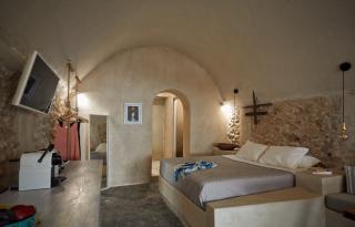 A cozy bedroom featuring a stone wall bed private hot tub and veranda in oia santorini perfect for relaxation hu12261124276558867968.jpg