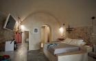 A cozy bedroom featuring a stone wall bed private hot tub and veranda in oia santorini perfect for relaxation hu 3da9d0ca2c5389e7.jpg