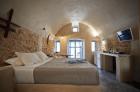 A cozy bedroom in oia santorini featuring a bed tv private hot tub and a charming veranda with a courtyard hu bcae721b8731dd61.jpg