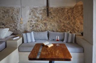 A cozy couch with a table and wine glass set in a luxurious oia accommodation with a private hot tub and veranda hu 634c321c0dd17989.jpg