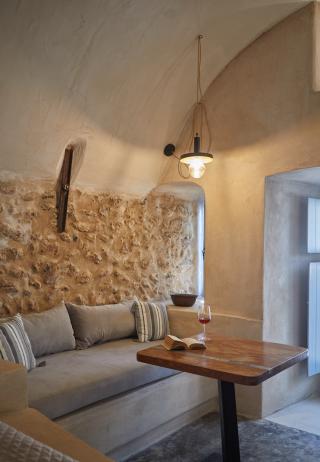 A cozy living room featuring a couch and table part of a cellar accommodation in oia santorini with a private hot tub hu1922512403577126288.jpg