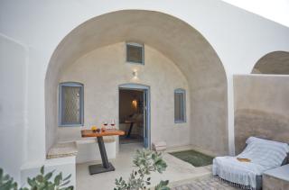 A cozy patio with a table and chair leading to a door set in oia santorini featuring a private hot tub and courtyard hu 75e4bbeed8440cc9.jpg
